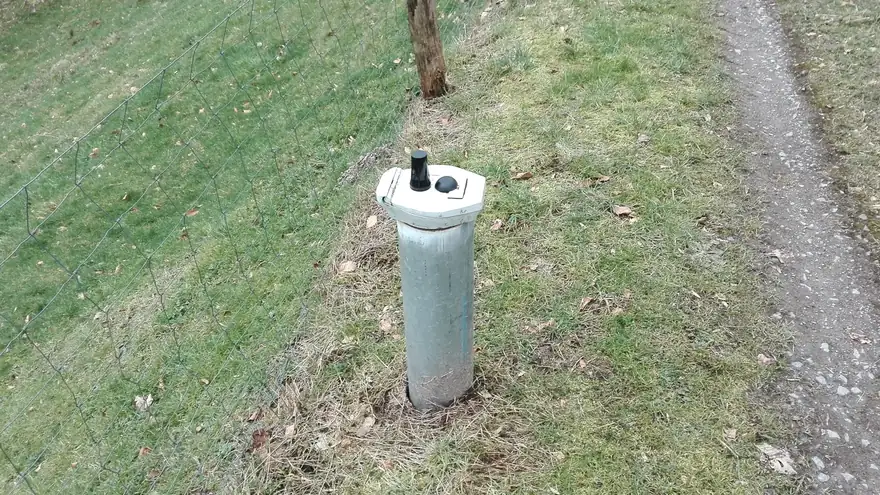 Grundwassermessstelle mit Schutzrohr und Verschlusskappe an einem Feldweg