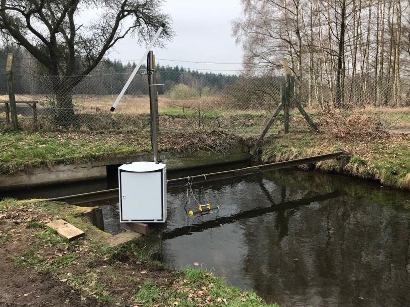Pegelschrank am eingezäunten Wassergraben in der Heide, Mess­einrichtung im Schutzgehäuse