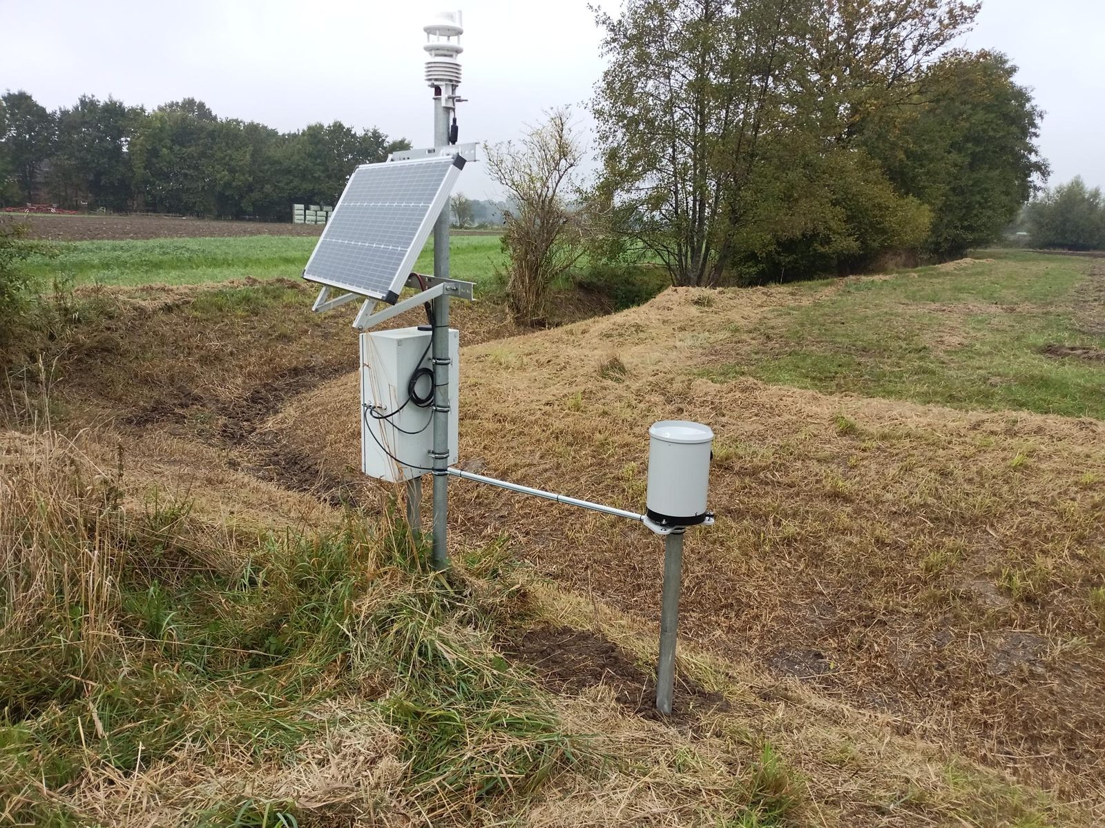 Klimastation mit Niederschlagssensor und Solar­panel am Feldrand bei Herbstwetter
